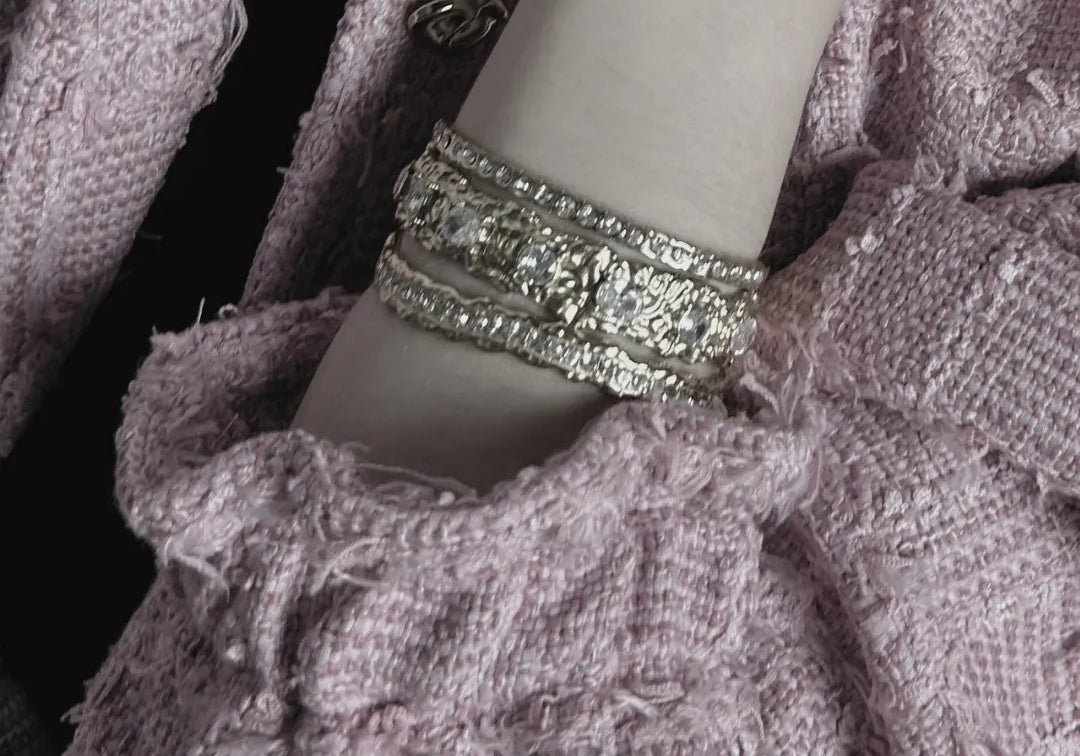Gros plan d'un vêtement en tissu texturé avec un bracelet en argent sur le bras d'un mannequin.